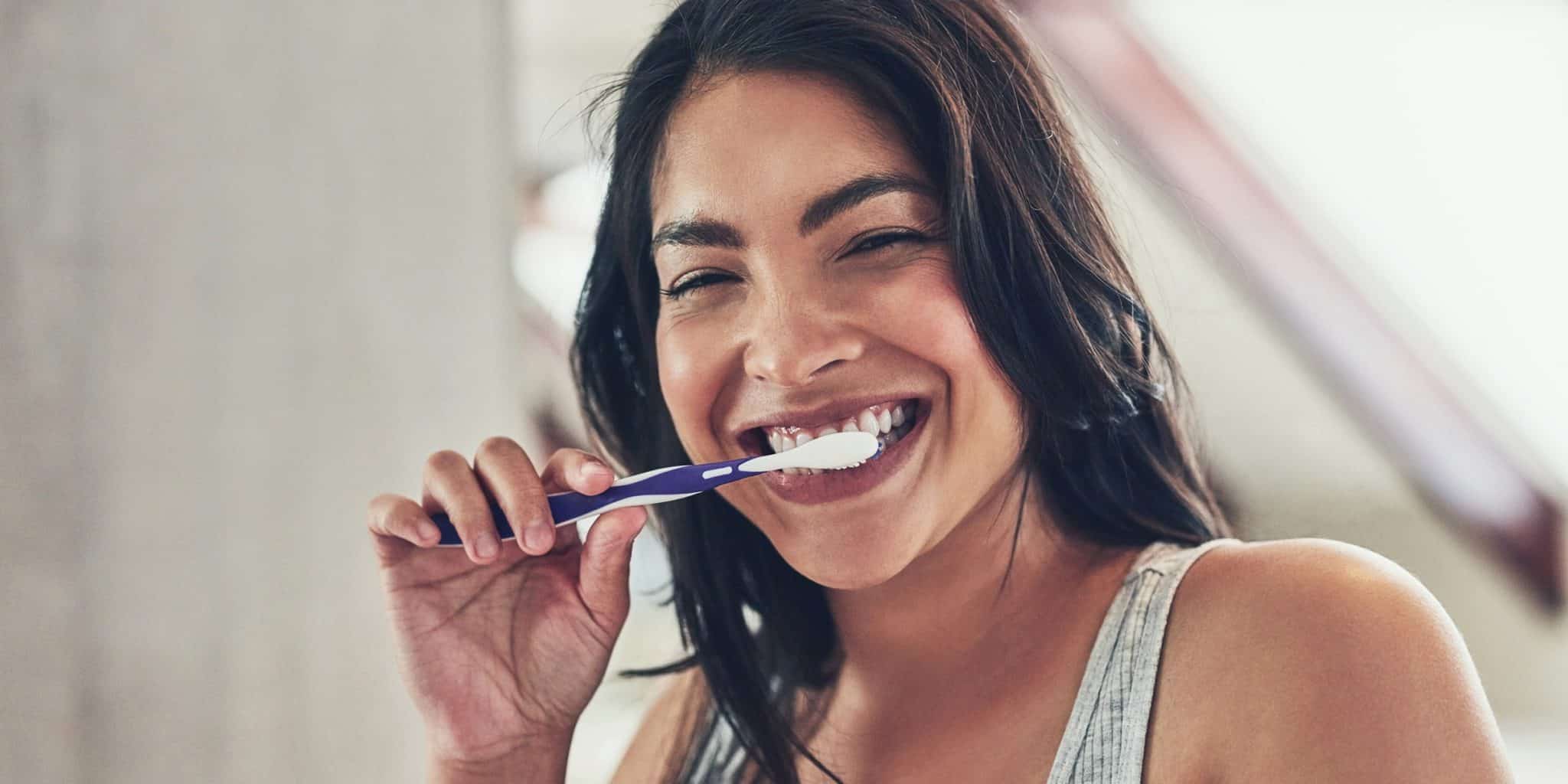 A person brushing their teeth with charcoal paste, trying the latest teeth whitening trend.
