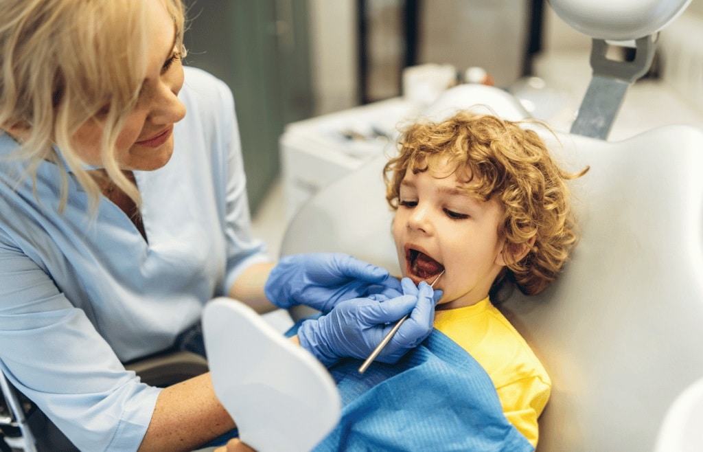A child sitting in a dentist's chair, receiving a dental examination