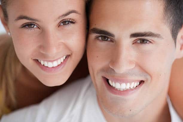 A happy couple showcasing their bright, healthy smiles after neuromuscular dentistry treatment.
