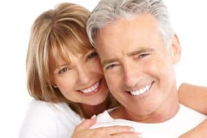 A happy couple with confident smiles showcasing the benefits of dental implants.