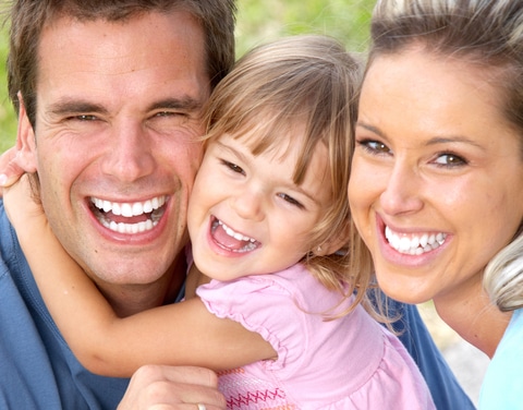 A happy family showcasing their beautiful smiles, emphasizing the importance of dental care.