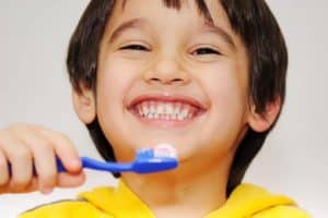 Smiling toddler with healthy teeth and toothbrush.